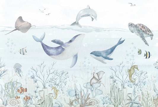Papel tapiz mural infantil con ilustración de ballenas, tortugas y arrecife marino en tonos celestes suaves.